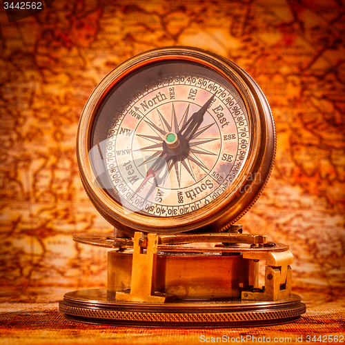 Image of Vintage compass lies on an ancient world map.