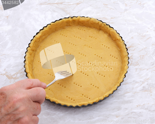 Image of Woman finishes pricking holes in a pastry pie crust