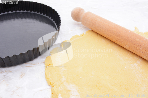 Image of Baking tin next to shortcrust pastry and rolling pin