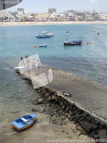 Image of editorial men are seen on pier Las Canteras Beach with hotels in