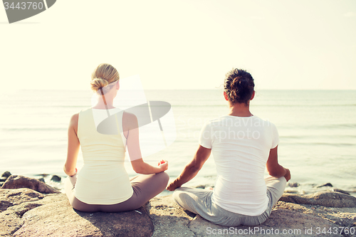 Image of couple making yoga exercises outdoors