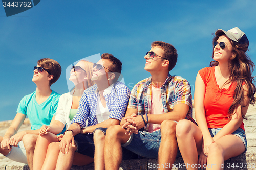 Image of group of smiling friends sitting on city street