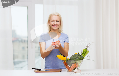 Image of smiling young woman cooking vegetables at home