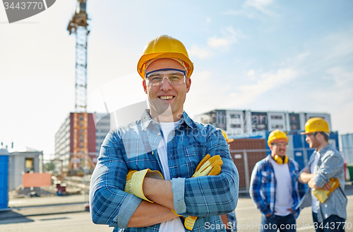 Image of group of smiling builders in hardhats outdoors