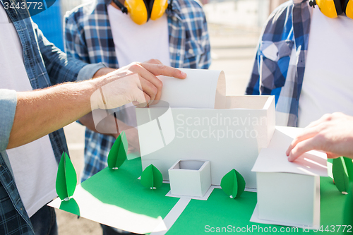 Image of close up of builders with paper house model