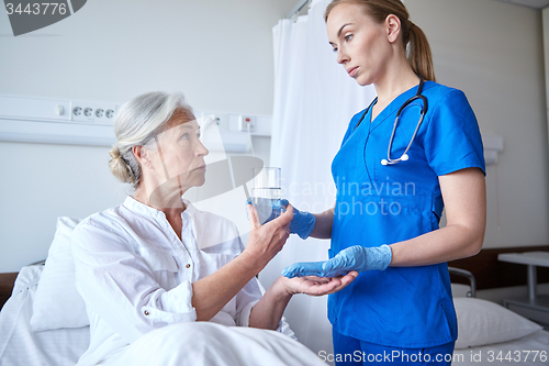 Image of nurse giving medicine to senior woman at hospital