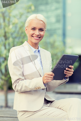 Image of smiling businesswoman with tablet pc outdoors