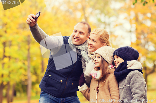 Image of happy family with camera in autumn park