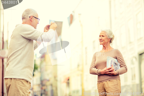Image of senior couple photographing on city street