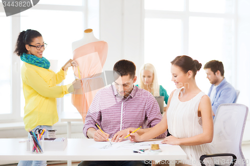 Image of smiling fashion designers working in office