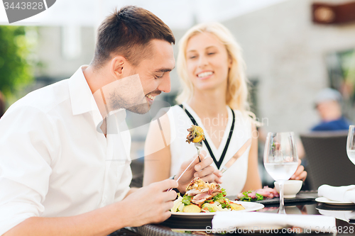 Image of happy couple eating dinner at restaurant terrace
