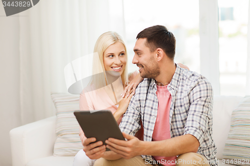 Image of smiling happy couple with tablet pc at home