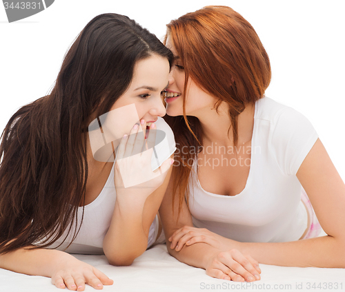 Image of two smiling girls whispering gossip