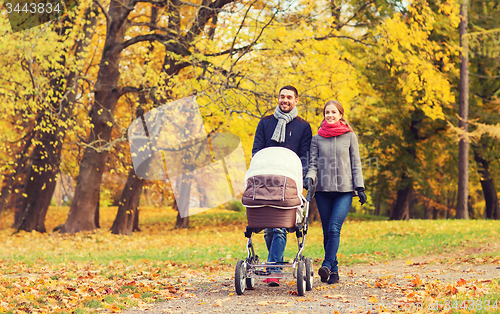 Image of smiling couple with baby pram in autumn park