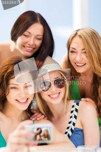 Image of girls taking photo in cafe on the beach