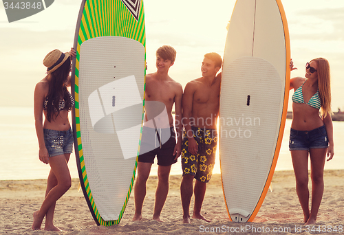 Image of smiling friends in sunglasses with surfs on beach