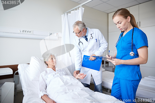 Image of doctor and nurse visiting senior woman at hospital