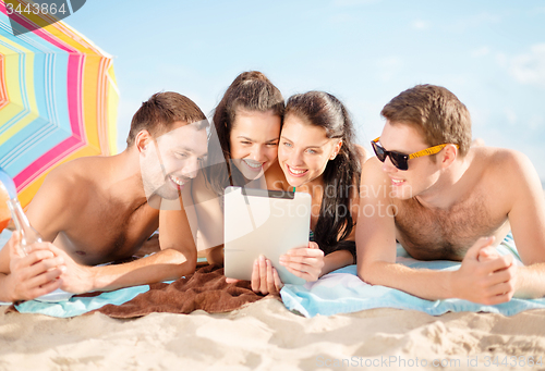 Image of happy friends with tablet pc on beach