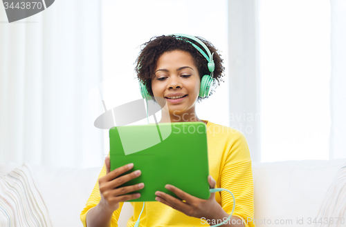Image of happy african woman with tablet pc and headphones