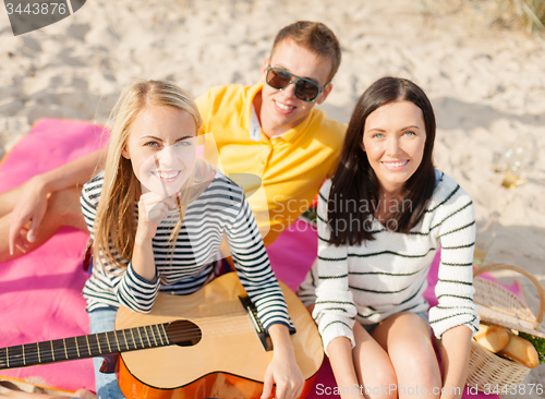 Image of group of happy friends playing guitar on beach
