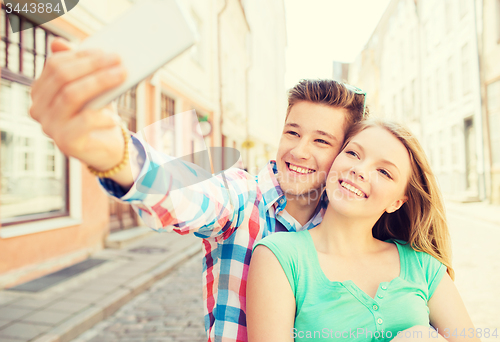 Image of smiling couple with smartphone in city