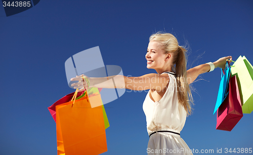 Image of smiling woman with shopping bag rising hands