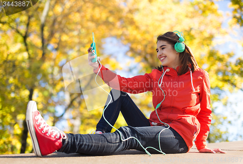 Image of happy young woman with smartphone and headphones