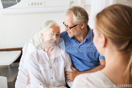 Image of happy family visiting senior woman at hospital