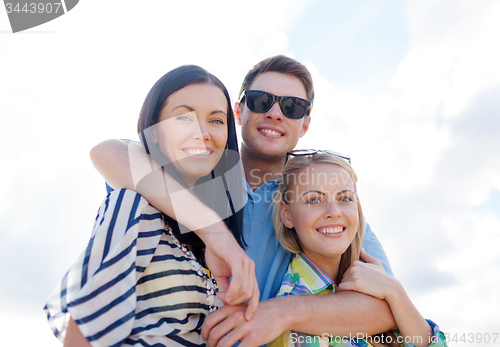 Image of group of happy friends hugging over sky background