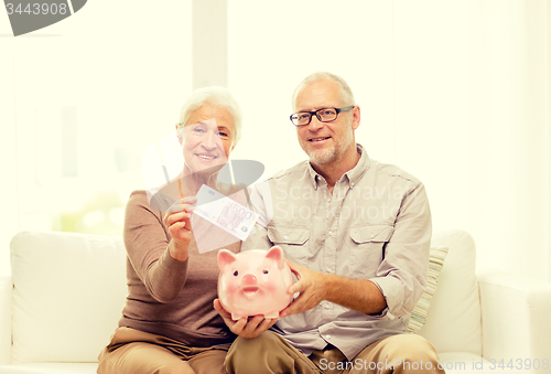 Image of senior couple with money and piggy bank at home