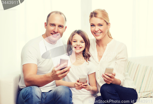 Image of parents and little girl with smartphones at home