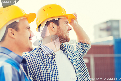 Image of group of smiling builders in hardhats outdoors