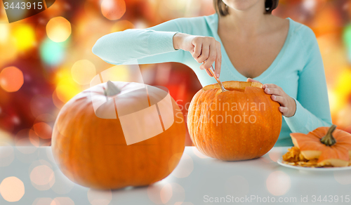 Image of close up of woman carving pumpkins for halloween