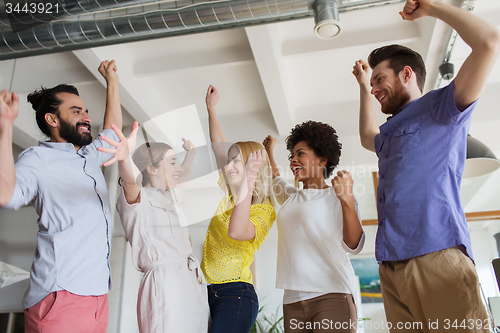 Image of happy creative team celebrating victory in office