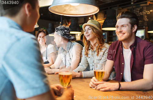 Image of happy friends drinking beer and talking at bar