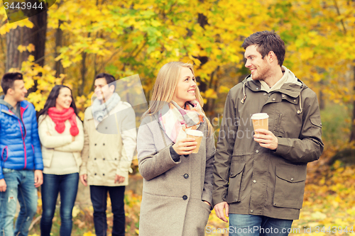 Image of group of smiling friend with coffee cups in park