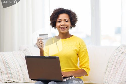 Image of happy african woman with laptop and credit card