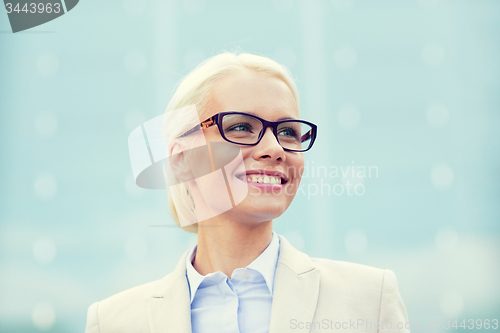 Image of young smiling businesswoman over office building