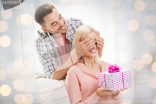 Image of happy man giving woman gift box at home