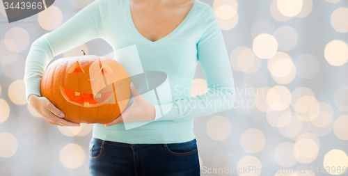 Image of close up of woman with carved halloween pumpkin