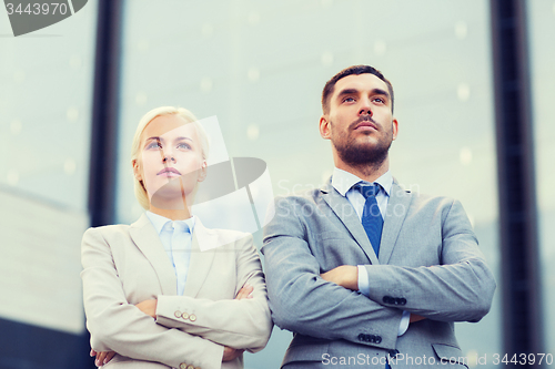 Image of serious businessmen standing over office building