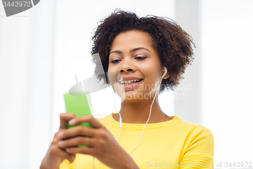 Image of happy african woman with smartphone and earphones