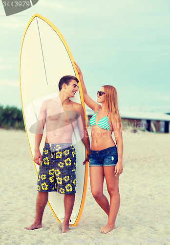 Image of smiling couple in sunglasses with surfs on beach