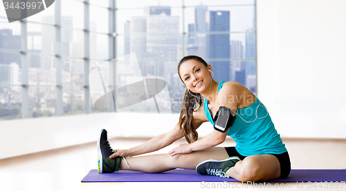 Image of smiling woman stretching leg on mat over gym