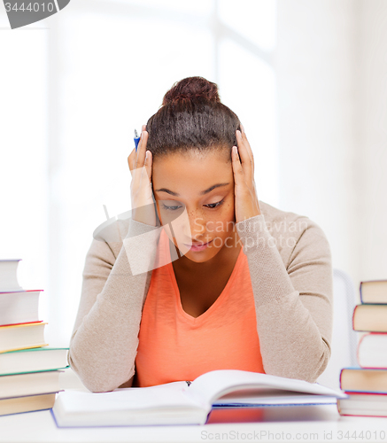 Image of tired student with books and notes