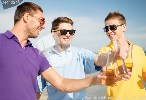 Image of happy friends with beer bottles on beach