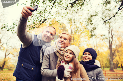 Image of happy family with camera in autumn park