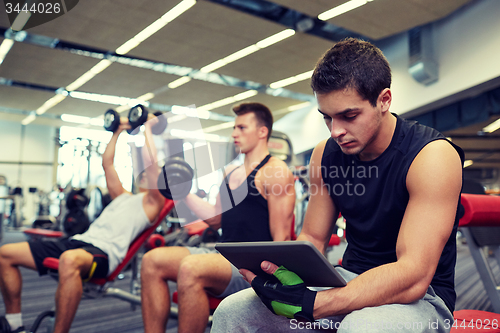 Image of group of men with tablet pc and dumbbells in gym