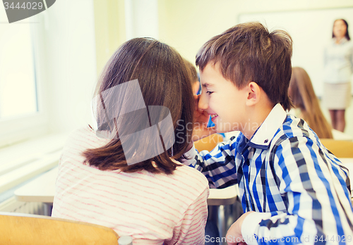 Image of smiling schoolgirl whispering to classmate ear