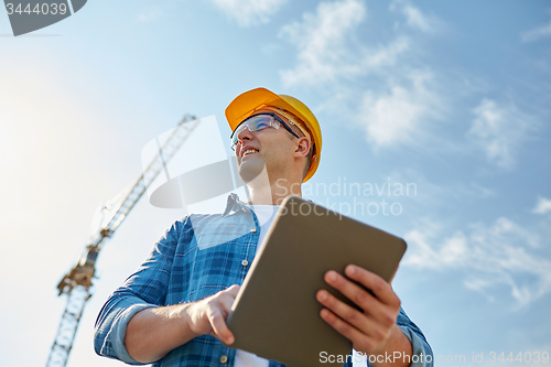 Image of builder in hardhat with tablet pc at construction